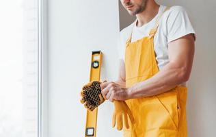 Handyman in yellow uniform preparing for work indoors. House renovation conception photo