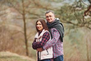 Happy mature couple standing and embracing each other outdoors in forest photo