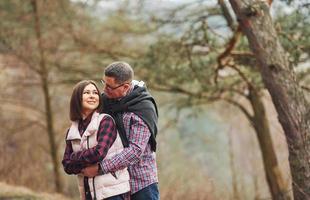 Happy mature couple standing and embracing each other outdoors in forest photo