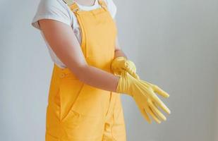 ama de casa con uniforme amarillo preparándose para pulir ventanas en el interior. concepción de renovación de la casa foto