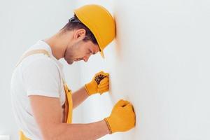 un manitas deprimido con uniforme amarillo se para contra la pared. concepción de renovación de la casa foto