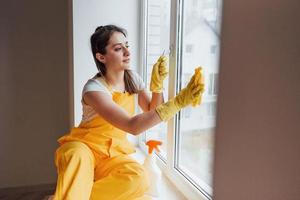 Housewife in yellow uniform cleaning windows. House renovation conception photo