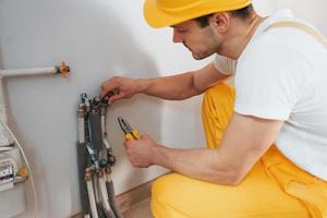 Handyman in yellow uniform works indoors. House renovation conception. Installing new device photo