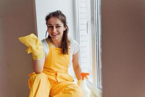 Housewife in yellow uniform cleaning windows. House renovation conception photo