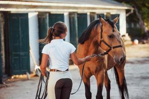 Getting ready for the ride. Horsewoman in white uniform with her horse at farm. Ready for the ride photo