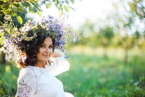 hermosa mujer joven con corona de flores en el jardín foto