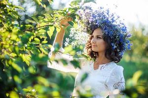 beautiful young woman with flower wreath in the garden photo