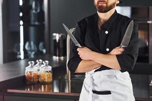 Professional young chef cook in uniform standing and preparing for the work on kitchen photo