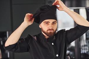 Professional young chef cook in uniform standing on the kitchen photo