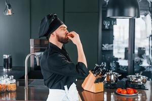 Side view of professional young chef cook in uniform that standing on the kitchen photo