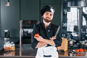 Portrait of professional young chef cook in uniform that posing for camera on the kitchen photo