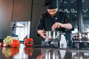 Un joven chef profesional uniformado tiene un día ajetreado en la cocina foto