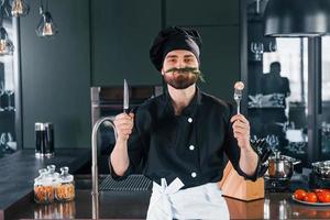 Portrait of professional young chef cook in uniform that posing for camera on the kitchen photo