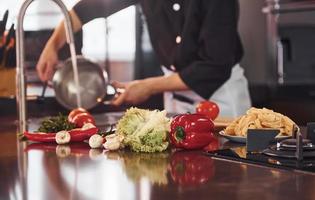 Using equipment. Professional young chef cook in uniform working on the kitchen with vegetables photo