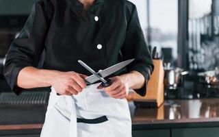 Professional young chef cook in uniform standing and preparing for the work on kitchen photo