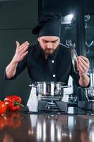 Un joven chef profesional uniformado tiene un día ajetreado en la cocina foto