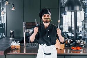 Portrait of professional young chef cook in uniform that posing for camera on the kitchen photo