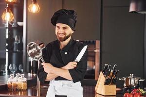 Portrait of professional young chef cook in uniform that posing for camera on the kitchen photo