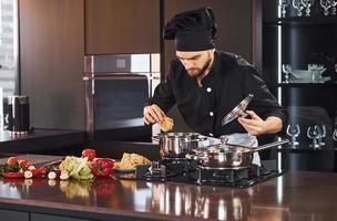 Using equipment. Professional young chef cook in uniform working on the kitchen with vegetables photo