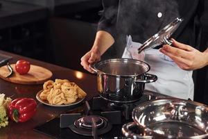 Using equipment. Professional young chef cook in uniform working on the kitchen with vegetables photo