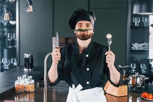 Portrait of professional young chef cook in uniform that posing for camera on the kitchen photo