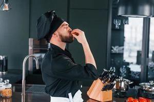 Side view of professional young chef cook in uniform that standing on the kitchen photo