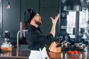 Side view of professional young chef cook in uniform that standing on the kitchen photo