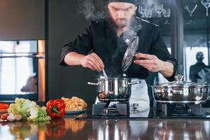 Cocinero profesional joven en uniforme trabajando en la cocina foto