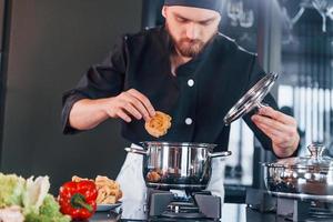 Preparing process. Professional young chef cook in uniform working on the kitchen photo