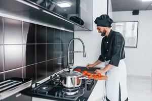 Professional young chef cook in uniform standing on the kitchen photo