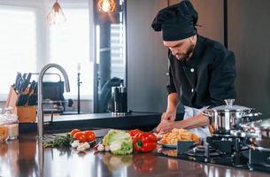 Professional young chef cook in uniform working on the kitchen photo