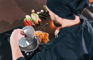 vista de cerca del joven chef profesional en uniforme que trabaja en la cocina foto