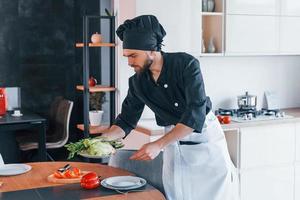 Professional young chef cook in uniform making salad on the kitchen photo