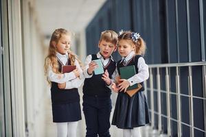 escolares en uniforme junto con el teléfono en el pasillo. concepción de la educación foto