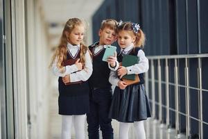 School kids in uniform together with phone in corridor. Conception of education photo