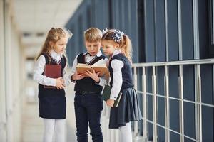 School kids in uniform together with books in corridor. Conception of education photo