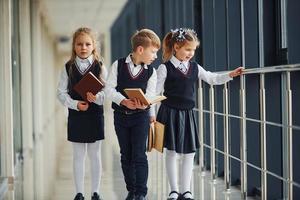 School kids in uniform together with books in corridor. Conception of education photo