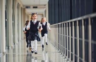 Active school kids in uniform running together in corridor. Conception of education photo