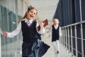 Active school kids in uniform running together in corridor. Conception of education photo