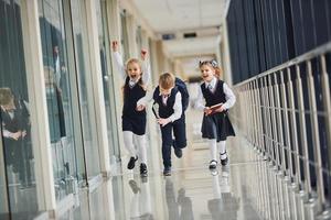 escolares activos en uniforme corriendo juntos en el corredor. concepción de la educación foto