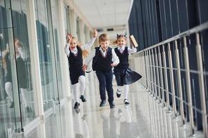 escolares activos en uniforme corriendo juntos en el corredor. concepción de la educación foto