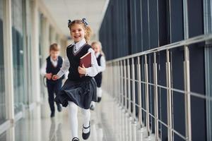 Active school kids in uniform running together in corridor. Conception of education photo