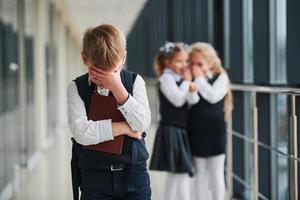 Little boy gets bullied. Conception of harassment. School kids in uniform together in corridor photo