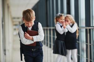 Little boy gets bullied. Conception of harassment. School kids in uniform together in corridor photo