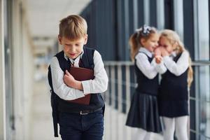 Little boy gets bullied. Conception of harassment. School kids in uniform together in corridor photo