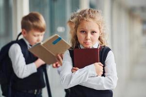 escolares en uniforme junto con libros en el pasillo. concepción de la educación foto