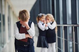 niño pequeño es intimidado. concepción del acoso. niños de la escuela en uniforme juntos en el pasillo foto