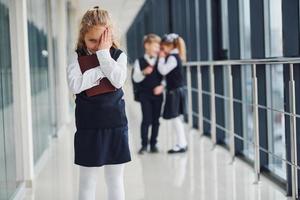 la niña es acosada. concepción del acoso. niños de la escuela en uniforme juntos en el pasillo foto