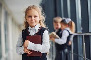 School kids in uniform together with books in corridor. Conception of education photo