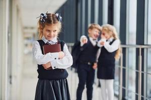 Little girl gets bullied. Conception of harassment. School kids in uniform together in corridor photo